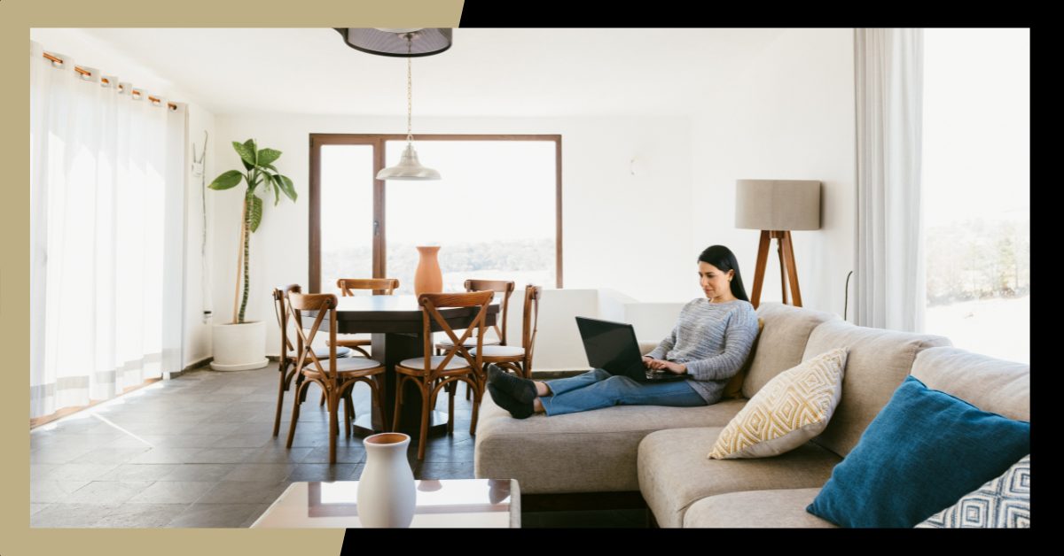 Long Term Rental Property - Woman sitting on a couch in living room working on her laptop.